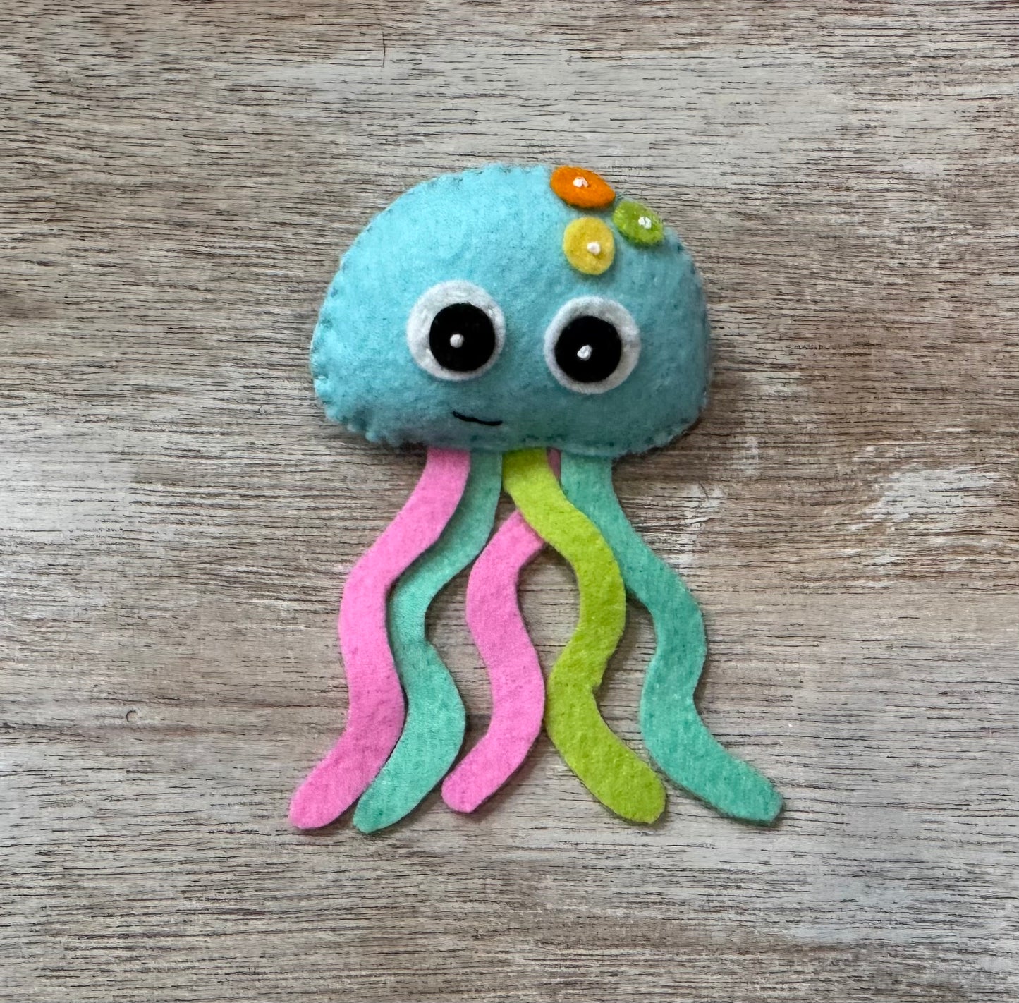 handmade and hand sewn felt creation by a little bit whimsy - brightly colors sea animals/ creatures. primary colors and pastels  smiling teal jellyfish