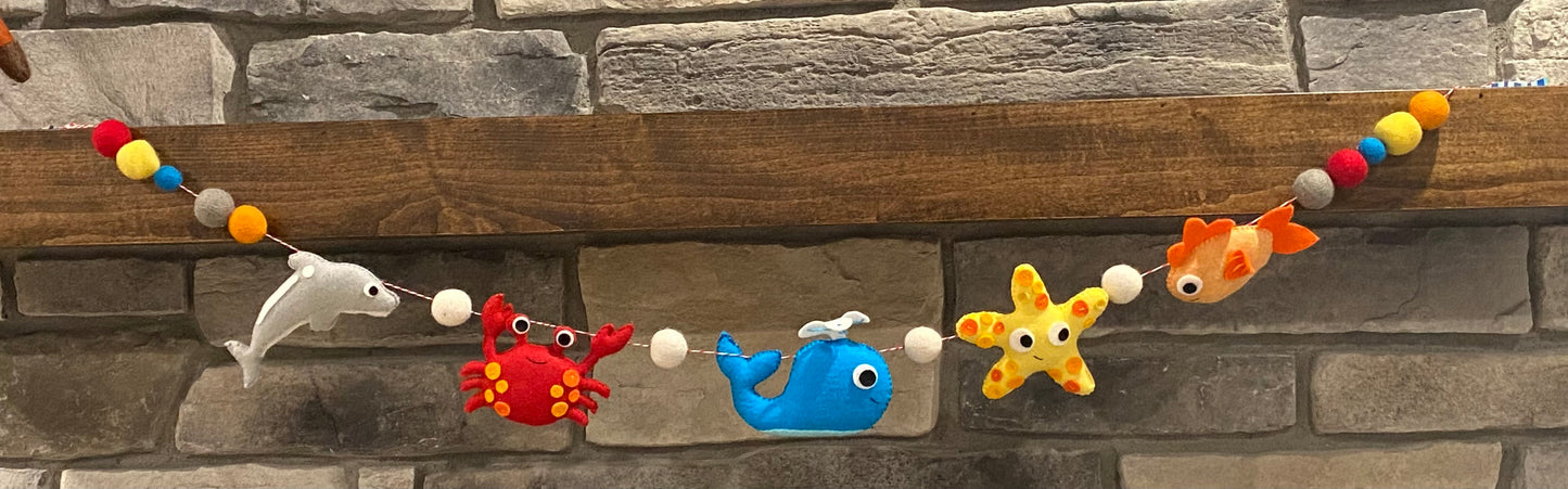 handmade and hand sewn felt creation by a little bit whimsy - brightly colors sea animals/ creatures. primary colors and pastels  , dolphin octopus, starfish, whale,  nemo fish,  seahorse with bright colored felt balls strung on garland