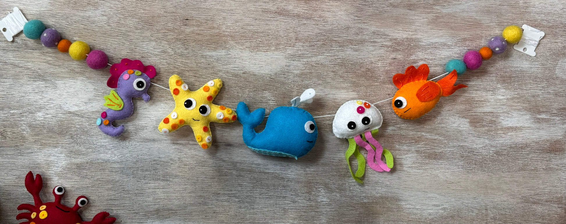 handmade and hand sewn felt creation by a little bit whimsy - brightly colors sea animals/ creatures. primary colors and pastels  , octopus, starfish, whale,  nemo fish,  seahorse with bright colored felt balls strung on garland